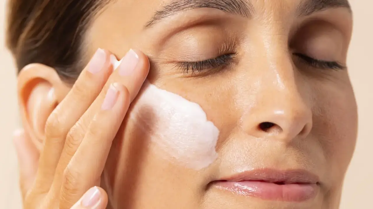 Application d'une crème hydratante contenant de l'acide polyglutamique sur le visage d'une femme.