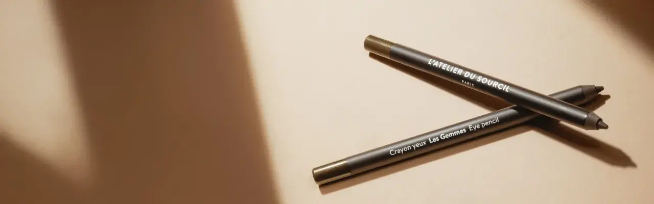 Deux crayons pour les yeux L'Atelier du Sourcil, un avant et un après, sur fond beige.