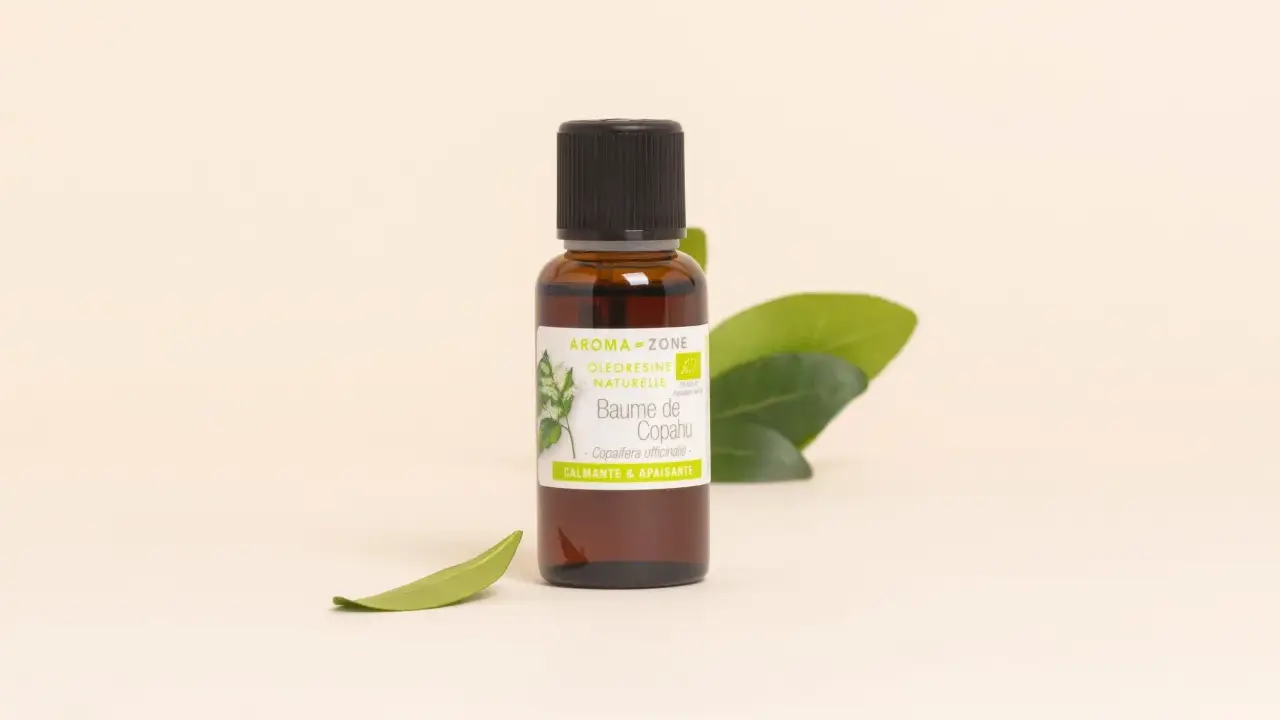 Flacon de baume de copahu, une oléorésine naturelle aux vertus calmantes et apaisantes, entouré de feuilles vertes.