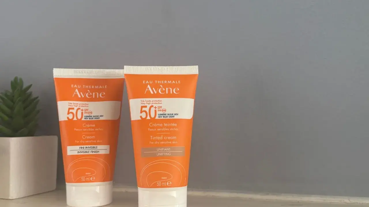 Deux tubes de spray solaire invisible SPF 50 Avène, l'un teinté, l'autre non, pour une protection optimale.