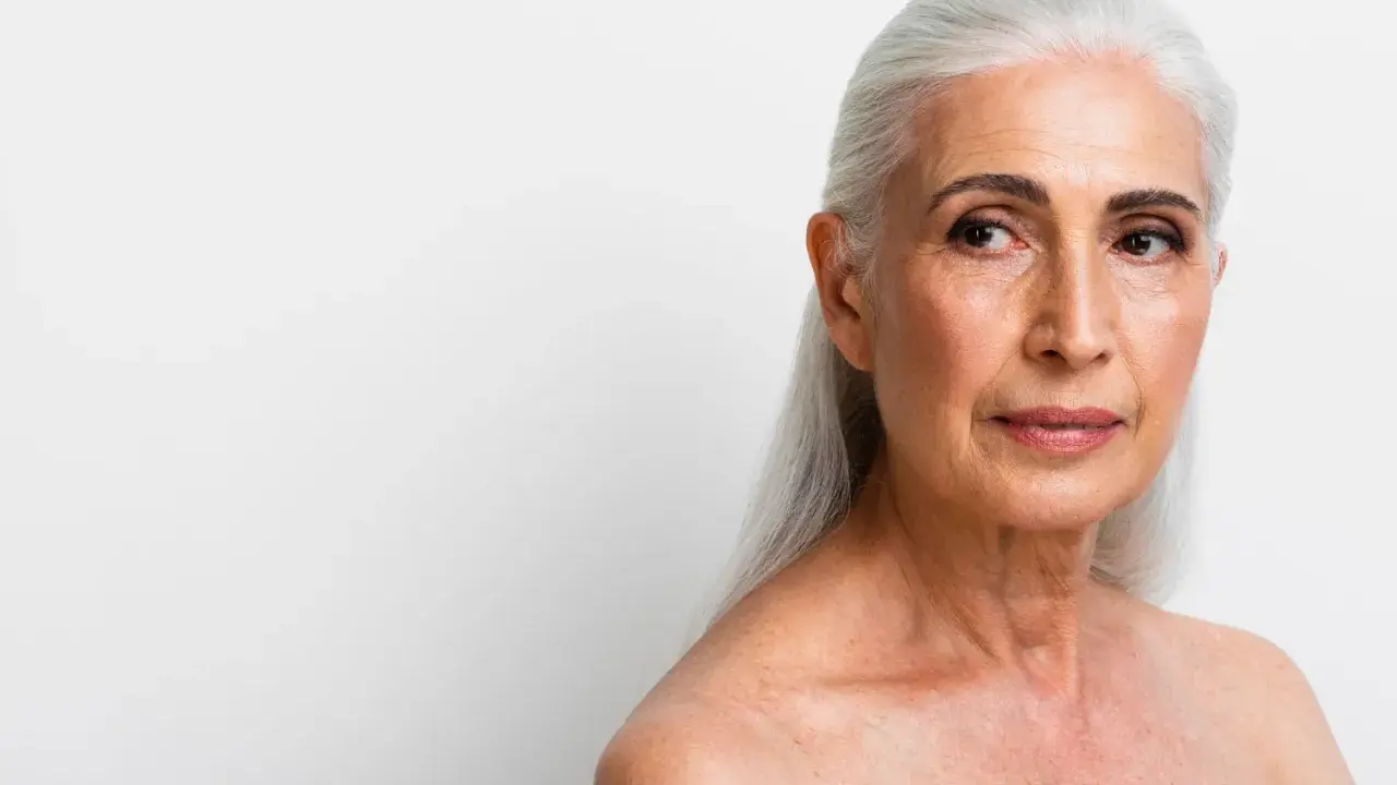 Visage femme 70 ans, cheveux argentés, regard pensif tourné vers la droite.