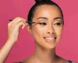 Une femme crée des "siren eyes" avec un eye-liner précis, son regard captivant promettant une beauté envoûtante.