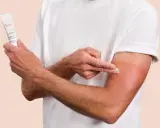 Un homme applique la crème Cicalfate+ sur son bras irrité, peut-être atteint de psoriasis, pour apaiser et réparer sa peau.