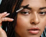 Une femme utilise une brosse pour coiffer son sourcil. La repousse d'un sourcil est une question de patience.