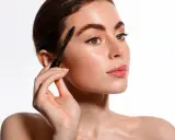Une femme applique un sérum pour cils avec une brosse. Apprenez comment appliquer serum cils pour des cils plus longs et plus épais.
