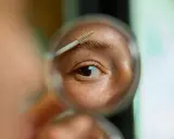 Gros plan sur un œil et un sourcil, une brosse à sourcils est utilisée pour les coiffer. La question est : est ce que les sourcils repoussent ?