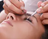 Pose de cils : quelle pince à épiler choisir pour un résultat parfait. Une esthéticienne applique des extensions de cils avec précision.