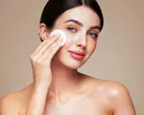 Une femme au maquillage impeccable utilise un coton pour se démaquiller, prouvant que le maquillage n'abîme pas la peau si on en prend soin.