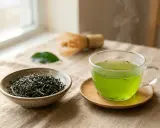 Une tasse de thé vert fumant, à côté d'un bol de feuilles de thé et d'un fouet, pour profiter des matcha bienfaits.