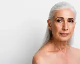 Visage femme 70 ans, cheveux argentés, regard pensif tourné vers la droite.