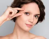 Une femme examine son visage, préoccupée par une possible alopécie sourcil.