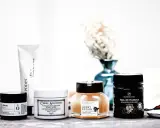 Plusieurs masques pour le visage, dont un masque au miel, sont disposés sur une table en bois.
