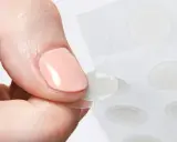 Une main retire délicatement un patch boutons d'une feuille, prêt à agir contre les imperfections.
