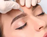 Main d'une esthéticienne réalisant des sourcils permanent effet naturel sur une cliente.
