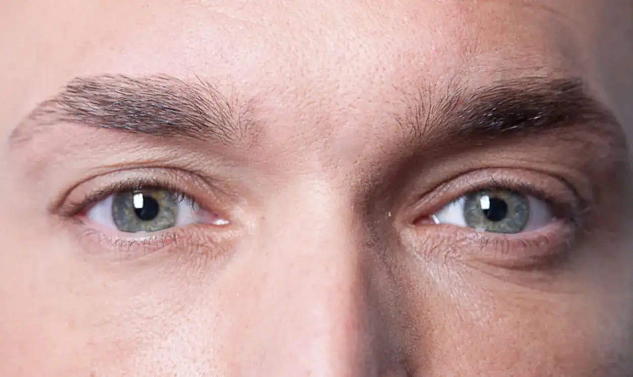 Gros plan sur les yeux d'un homme, mettant en valeur la forme naturelle de ses sourcils.