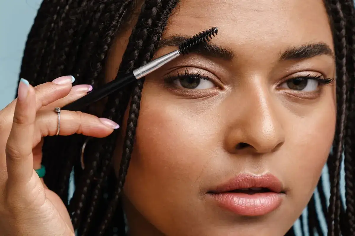 Une femme se brosse les sourcils avec une brosse à maquillage. La question est : est ce que les sourcils repoussent ?