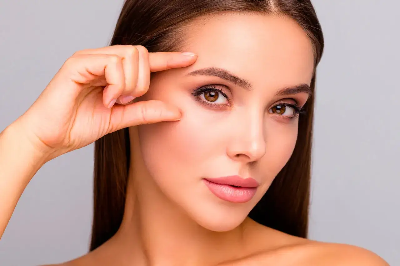 Une femme ajuste ses sourcils, soulignant le mode sourcils parfait pour un regard captivant.