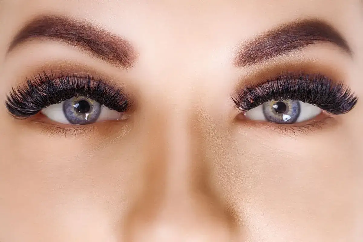 Yeux magnifiques avec pose volume russe cils, sourcils parfaitement dessinés et iris bleus captivants.
