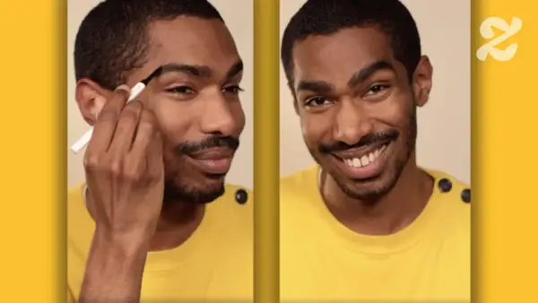 Un homme ajuste la forme de son sourcil avec un crayon. Il sourit, confiant dans son nouveau look.
